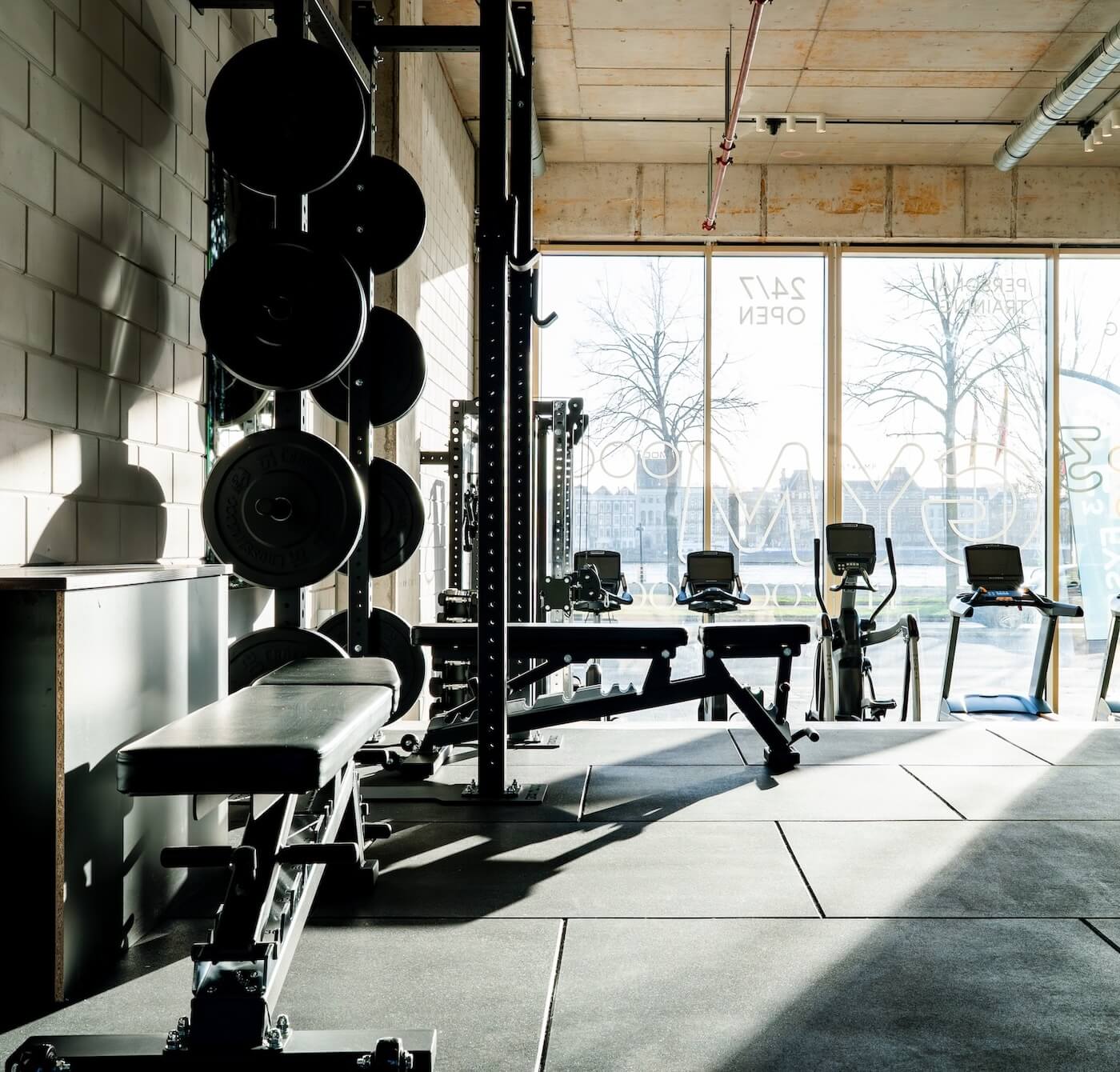 Overzicht van de trainingsvloer van F3 GYM met halterbanken en cardioapparatuur