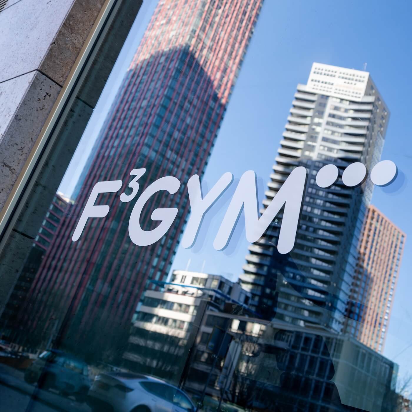Het logo van F3 GYM op de gevel aan de Hertekade, met de Red Apple op de achtergrond