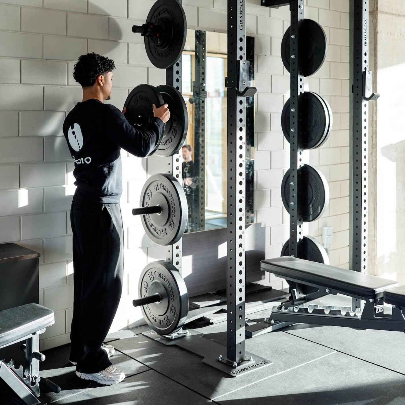 Trainer van F3 GYM laadt halterschijven op de squat rack in de krachtruimte
